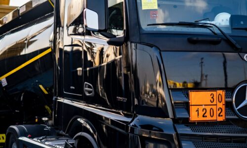 Black truck with a tanker, showcasing logistics and transportation in an industrial environment.