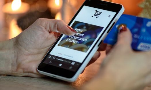 pexels-photo-230544-230544 Woman using smartphone for online shopping with credit card in hand, festive background lighting.