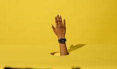 pexels-photo-5878870-5878870 A unique hand gesture breaking through yellow backdrop in a studio setting.