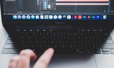 Crop unrecognizable male programmer typing on netbook while working on project and creating music