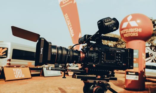 pexels-photo-9703183-9703183 High-end video camera setup at an outdoor car event, displaying advanced filming equipment.